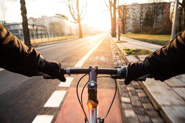 Radfahrende Person auf einem markierten Radweg im morgendlichen Stadtverkehr